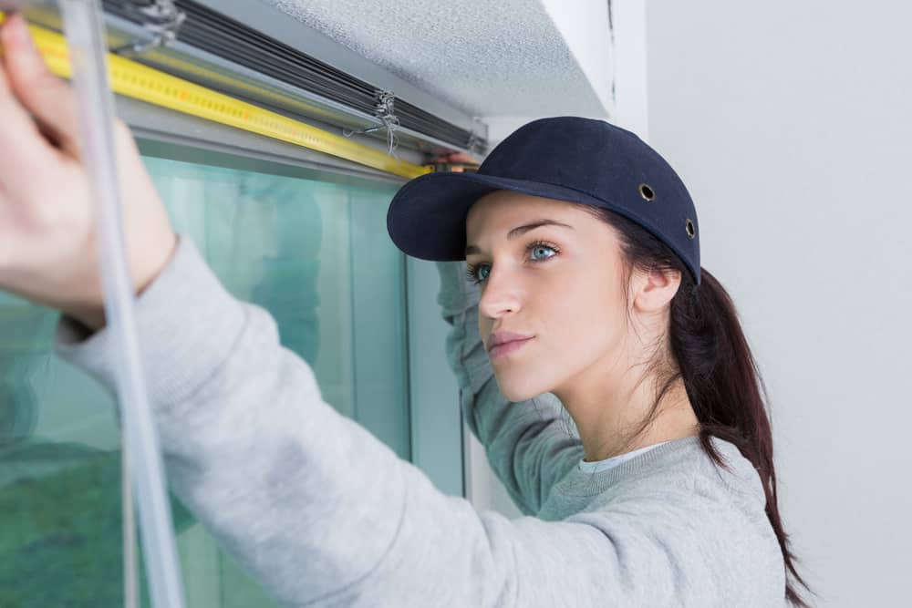 A woman using a measuring tape to measure a window for hunter douglas windo treatments